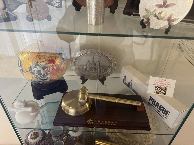 捷克參議院展出多項台灣致贈參議院代表的勳章與禮品，包含國安會秘書長吳釗燮贈送的外交紀念品（前左）、鋁合金製成的立法院「紀念議事槌」（前中），以及華航董事長高星潢在布拉格台北直航開通時致贈的禮物（前右）。
