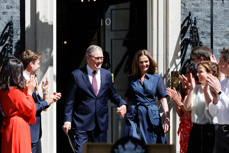 英國首相施凱爾（左）20日最後一次以首相身分步出唐寧街10號官邸，妻子維多利亞（右）伴隨，一同接受提早聚集在門外的支持者、執政團隊與公務體系成員鼓掌歡呼。
（英國首相府提供）