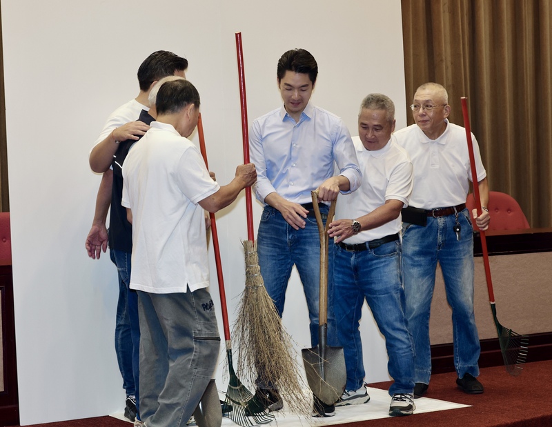 台北市長蔣萬安（右3）6日與台北市里長參選人拍攝宣傳照，多名參選人準備掃帚等工具跟蔣萬安一起拍照。